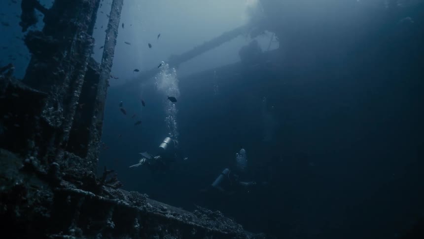 Divers at the bottom of the ocean amid a stranded ship
