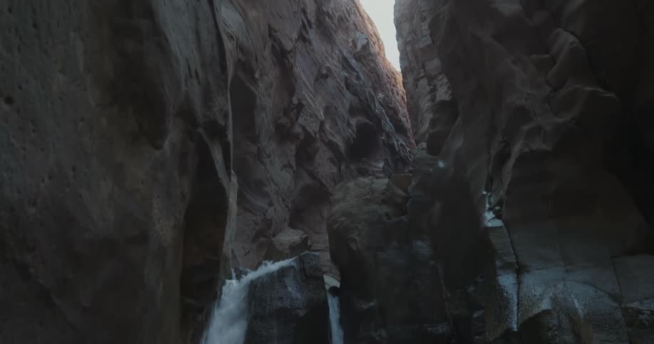 Panorama from inside a valley with water cascading in the midst of a river