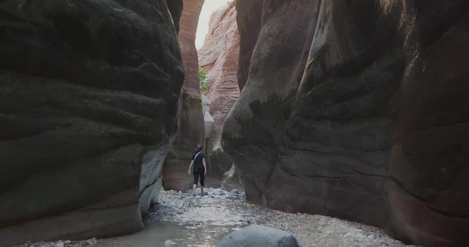 A woman walking along a small stream between gorges during the day