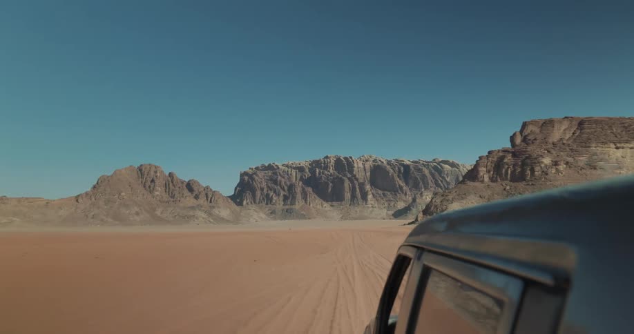 View of a car driving through the desert toward a valley
