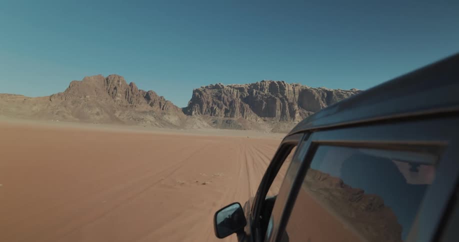 View of a car driving through the desert toward a valley