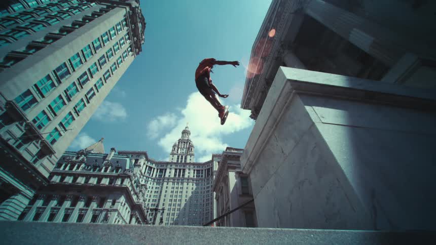 Panorama of a man jumping in midair amidst a city with buildings