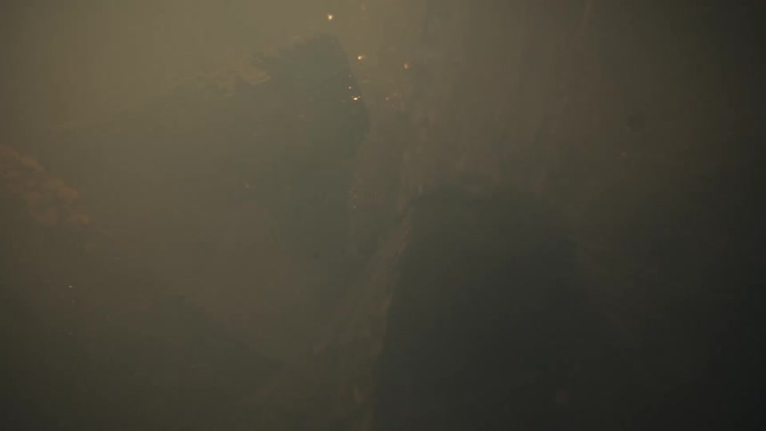 Water falling on burning wood logs and white steam smoke emerges