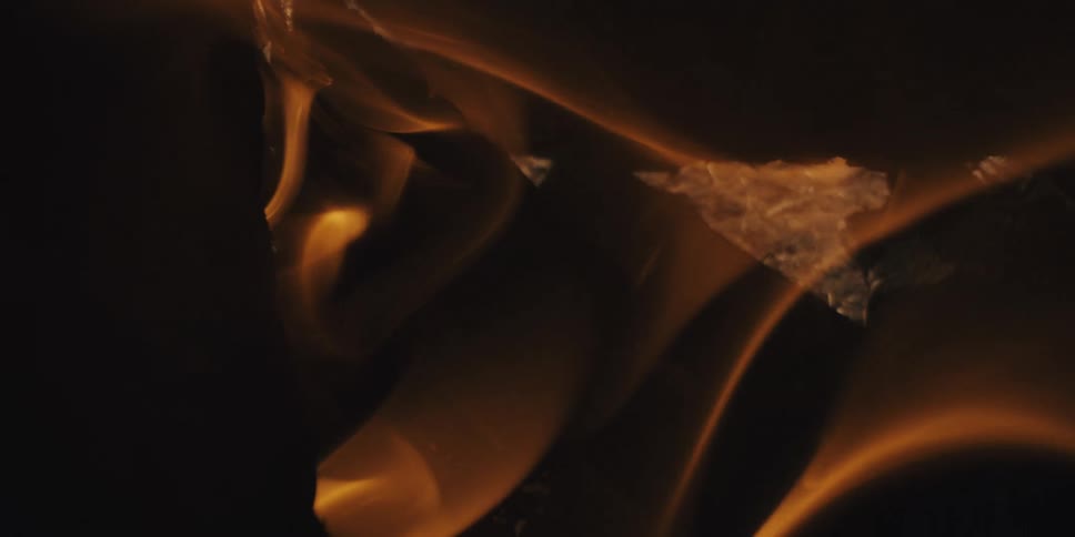 Extreme closeup of firewood on fire with embers expelling in slow motion