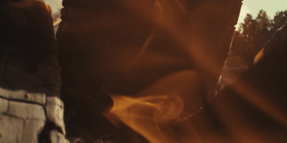 Extreme closeup of firewood on fire with embers expelling in slow motion and day