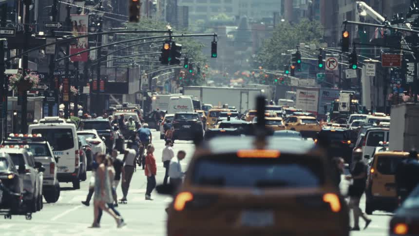 View of a traffic street in the middle of a metropolis with people walking and cars moving slowly