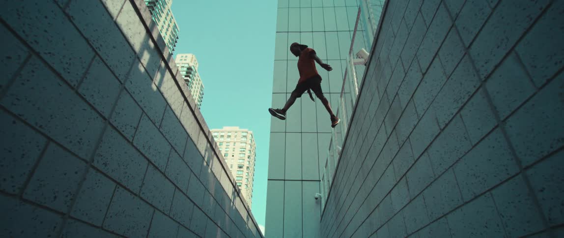 A man jumps across the steep gap in the city
