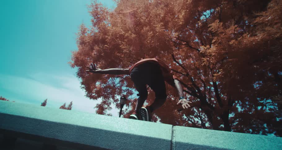 Man jumping off a structure in the city performing a parkour move