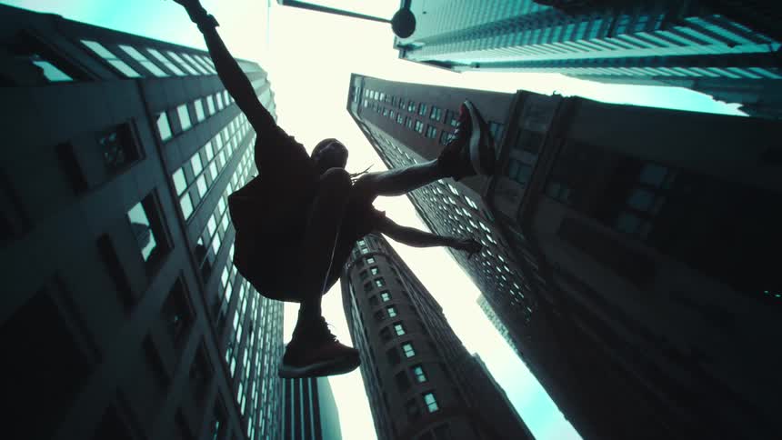 Amid towering skyscrapers a man leaps off the ground defying gravity momentarily