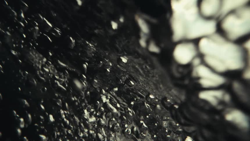 Closeup reveals water bubbles rising floating upward