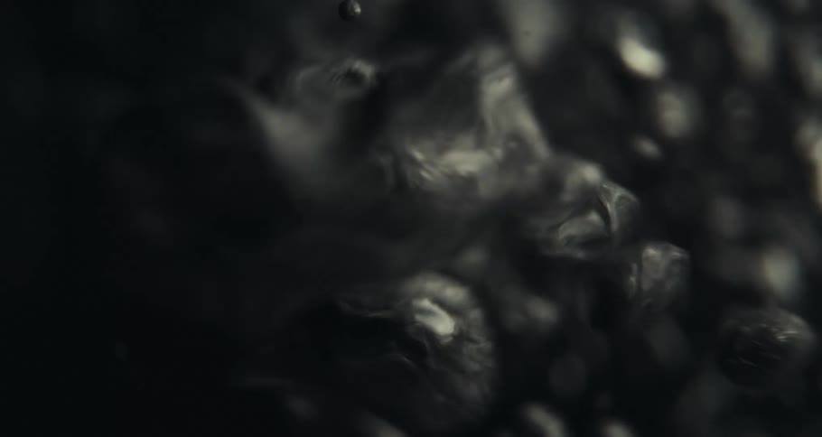 A black liquid with several bubbles coming together moving in an abstract way