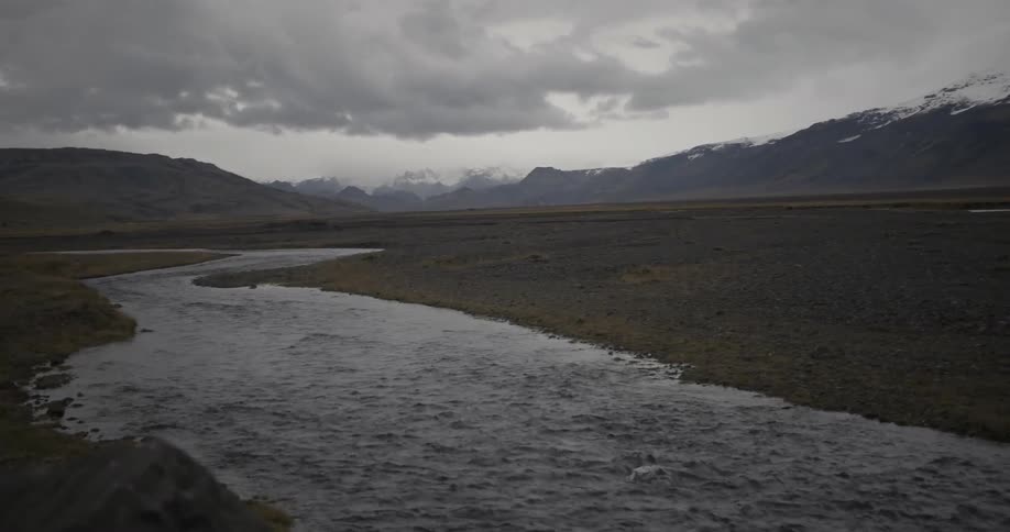 A river runs through a valley on a cloudy day