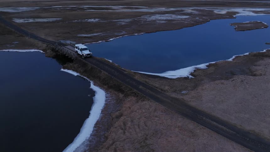 A vehicle passing over a bridge over a lake during the day