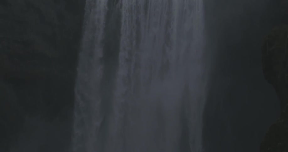 A waterfall between mountains on a cloudy day