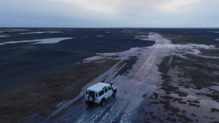 Car driving through a natural environment with black soil on a cloudy morning