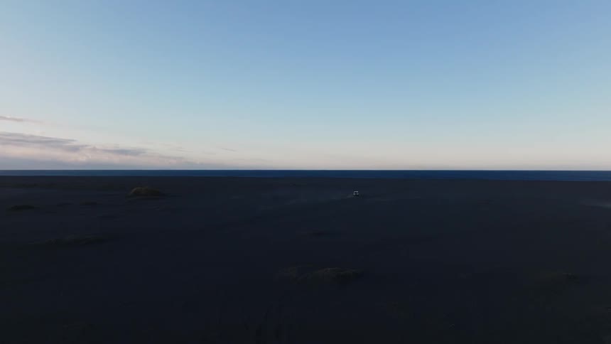 Panoramic view of a car driving in a natural environment on open ground under a dawn sky