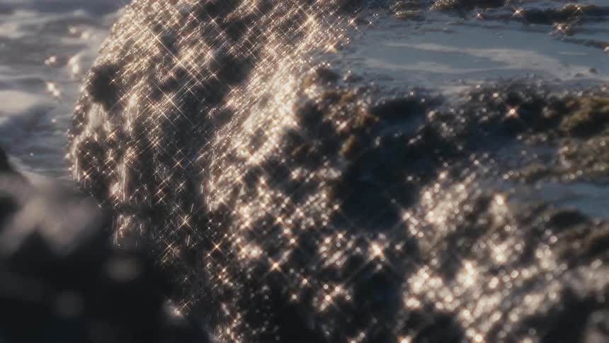 Ocean water flows over jagged rocks on a very sunny day