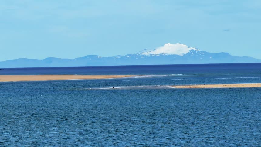 Sandbars in ocean with mountain on horizon
