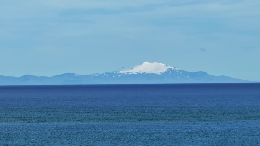 Aerial of the ocean with mountains on the horizon