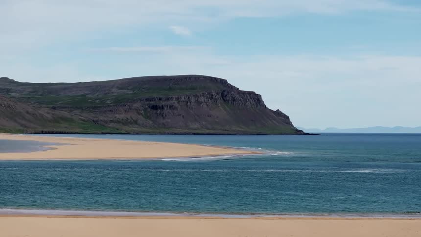 Panorama of a beach with sands amid the sea and the coastline on the horizon