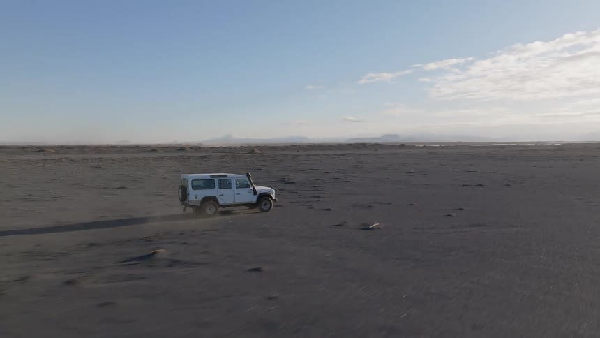 A truck is driving off road leaving a dust cloud behind