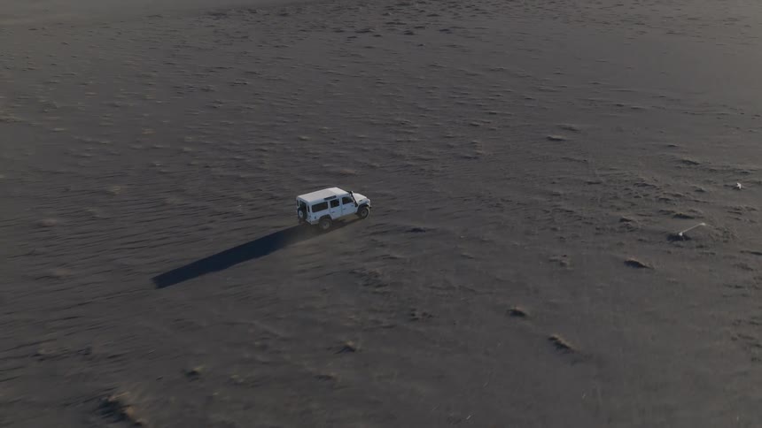 Aerial of a car driving through the desert during the day
