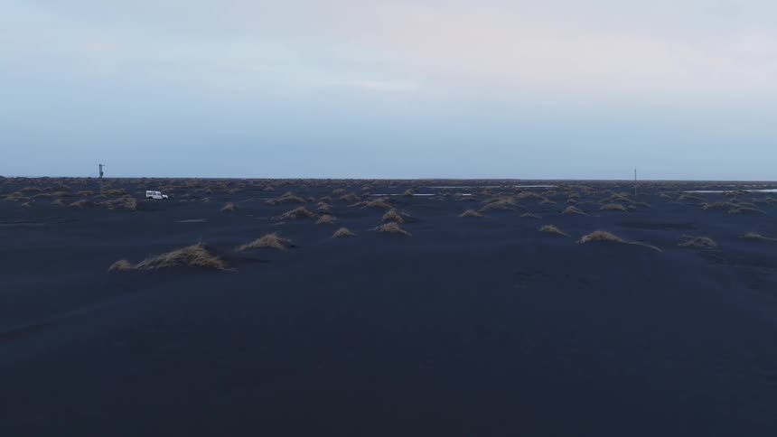 Aerial panorama of a jeep driving on black ground on a morning