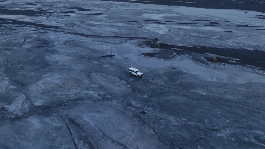 Aerial of a white jeep drives in the desert