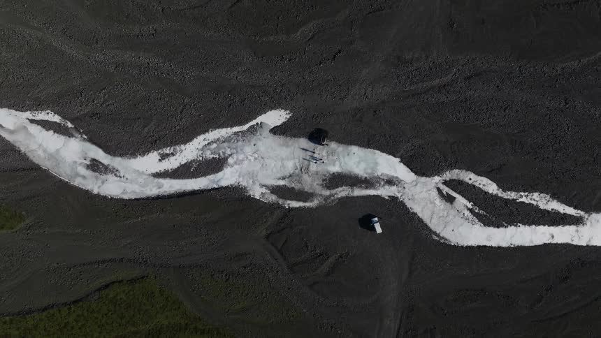 Aerial view of a trail of snow with people in the midst of nature