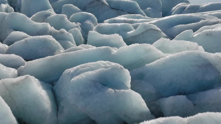 A large pile of ice next to a lake