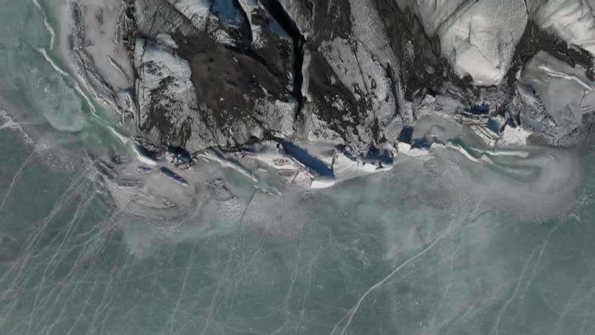 Top view of a frozen lake next to a snowcovered mountain