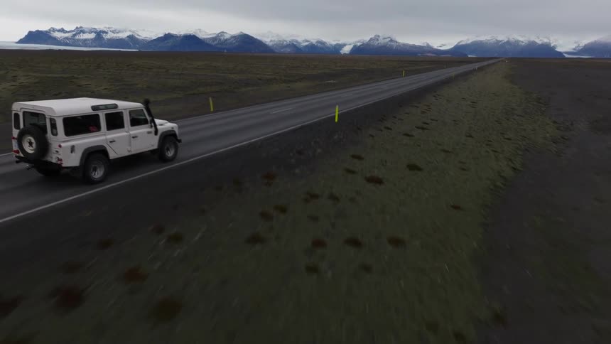 Aerial of a white jeep driving on country road on a cloudy day