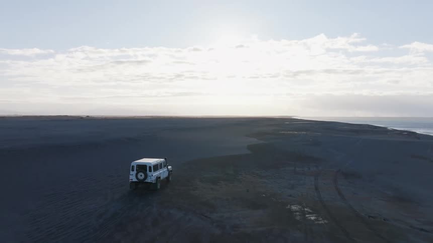 A car driving on a flat terrain near the sea coast