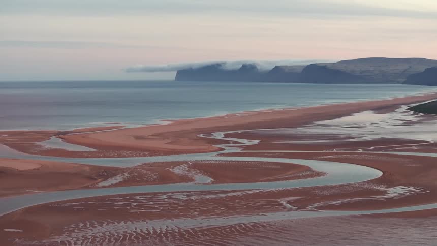 Aerial panorama of sand blending into the sea under a morning sky