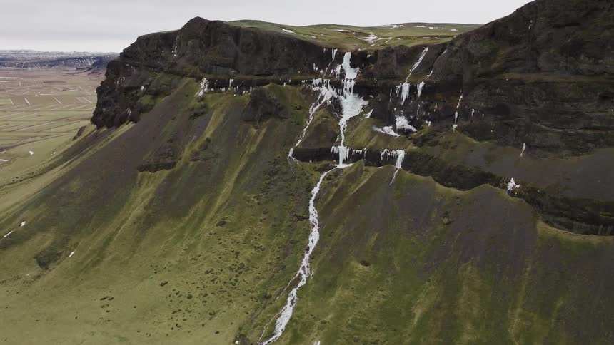Aerial of a solitary house standing close to a rugged mountain ridge and a river