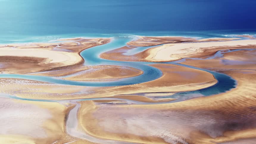 Aerial panorama of sand dunes next to a sea