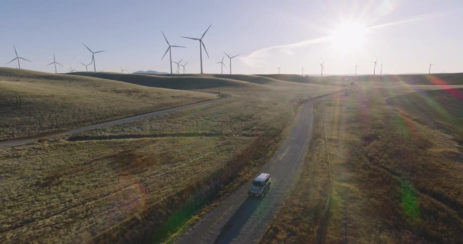 A van driving across a wind farm