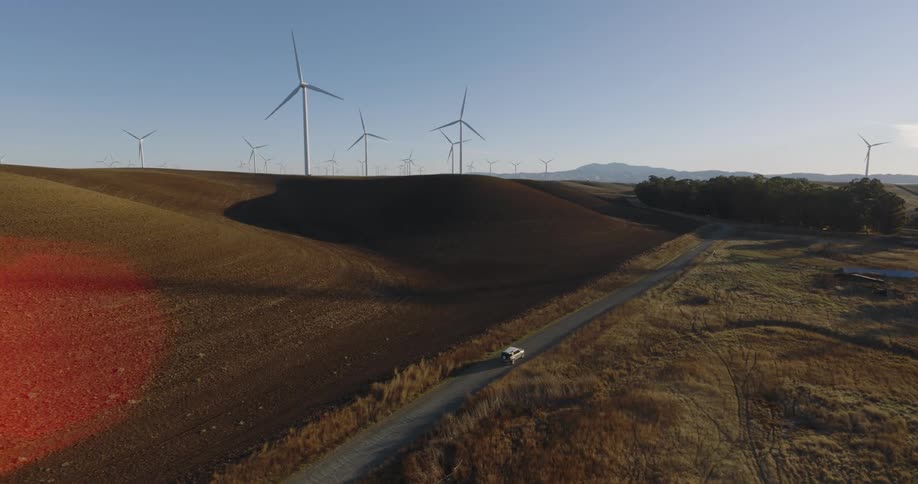 Vehicle drives along highway past windfarm on a foggy day