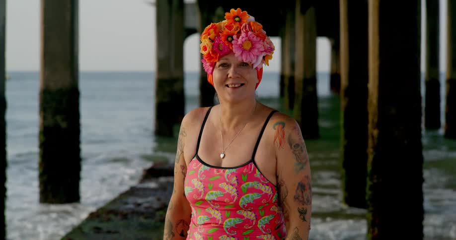 Happy tattooed woman wearing a colorful outfit under a pier