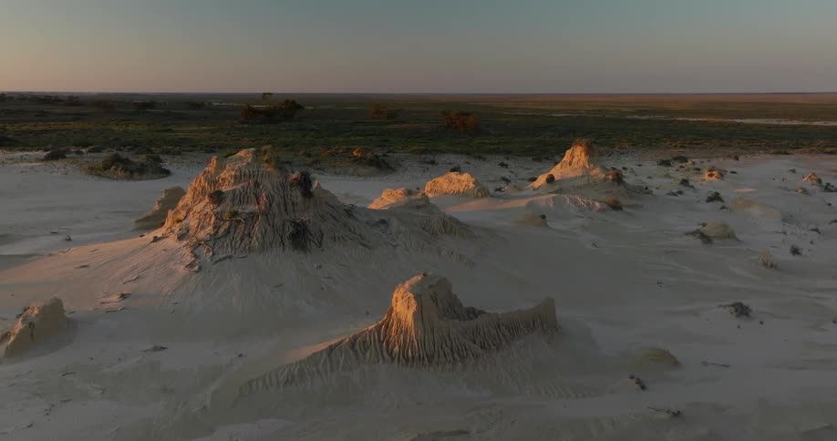 Panorama of small cliffs and desert terrain next to a grassland under a morning sky