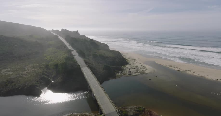 Aerial panorama of a beach along the edge of a road with a bridge
