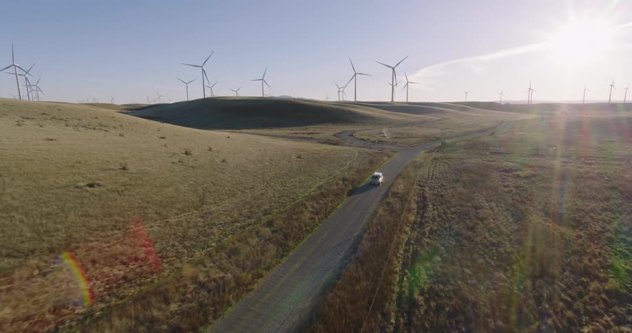 A vehicle is driving past the windmills