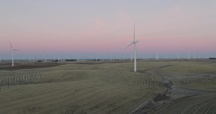 Aerial panorama of a location in fields with wind energy platforms under a purple dawn sky