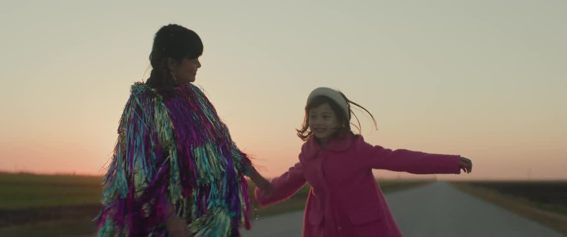 A woman and a girl dancing on a deserted farm road in the evening