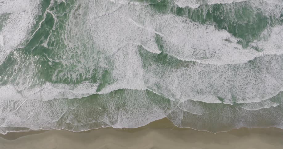 Aerial of ocean waves rolling into the shore in slow motion