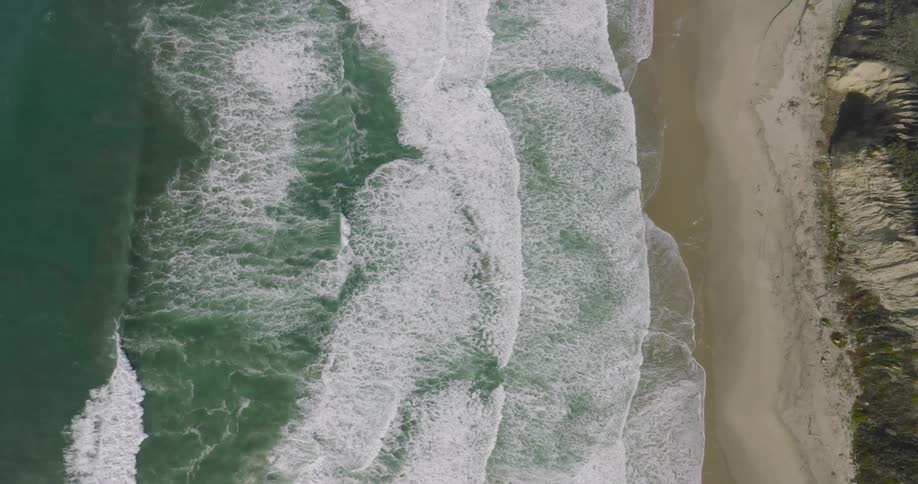 Aerial of a desert island with waves crashing on the shore