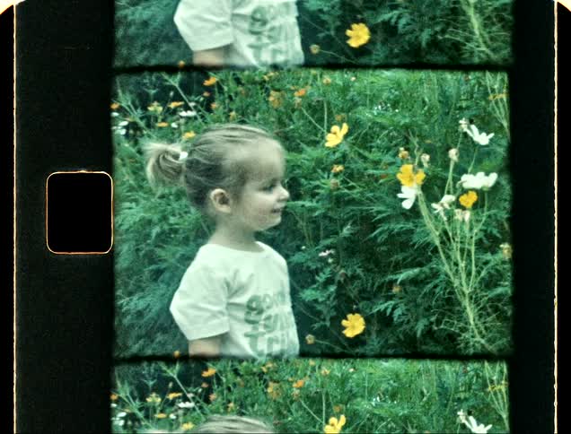A girl smells a flower and smiles