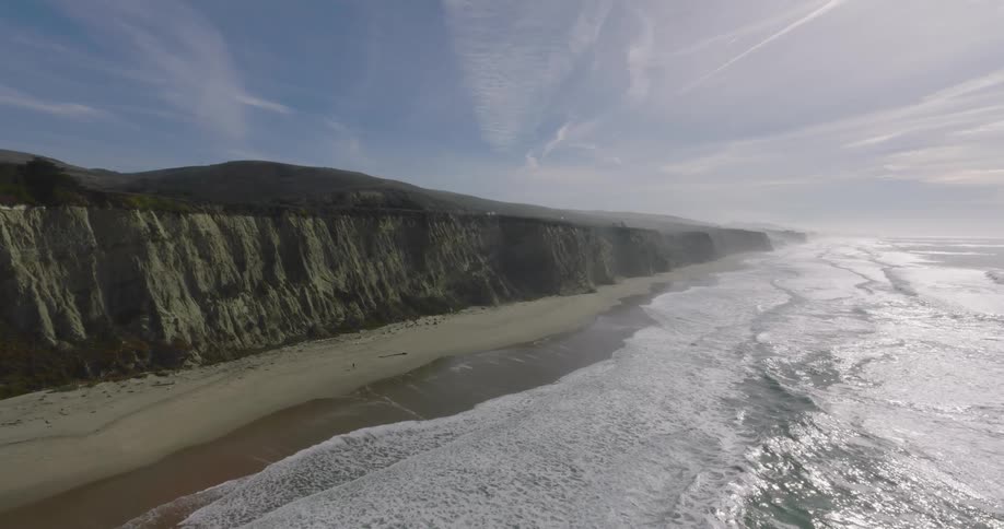 Aerial of a deserted beach with a cliff on a sunny day