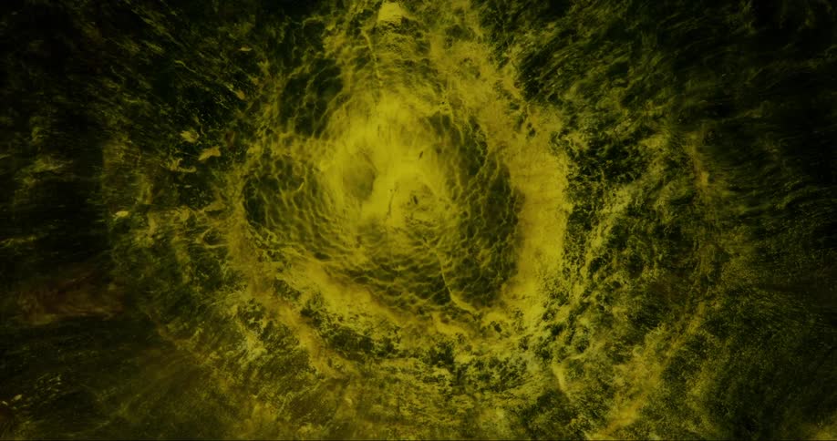Extreme closeup of an abstract fluid with yellowish and greenish hues boiling in slow motion