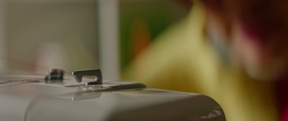 Detail view of thread being pulled into a sewing machine